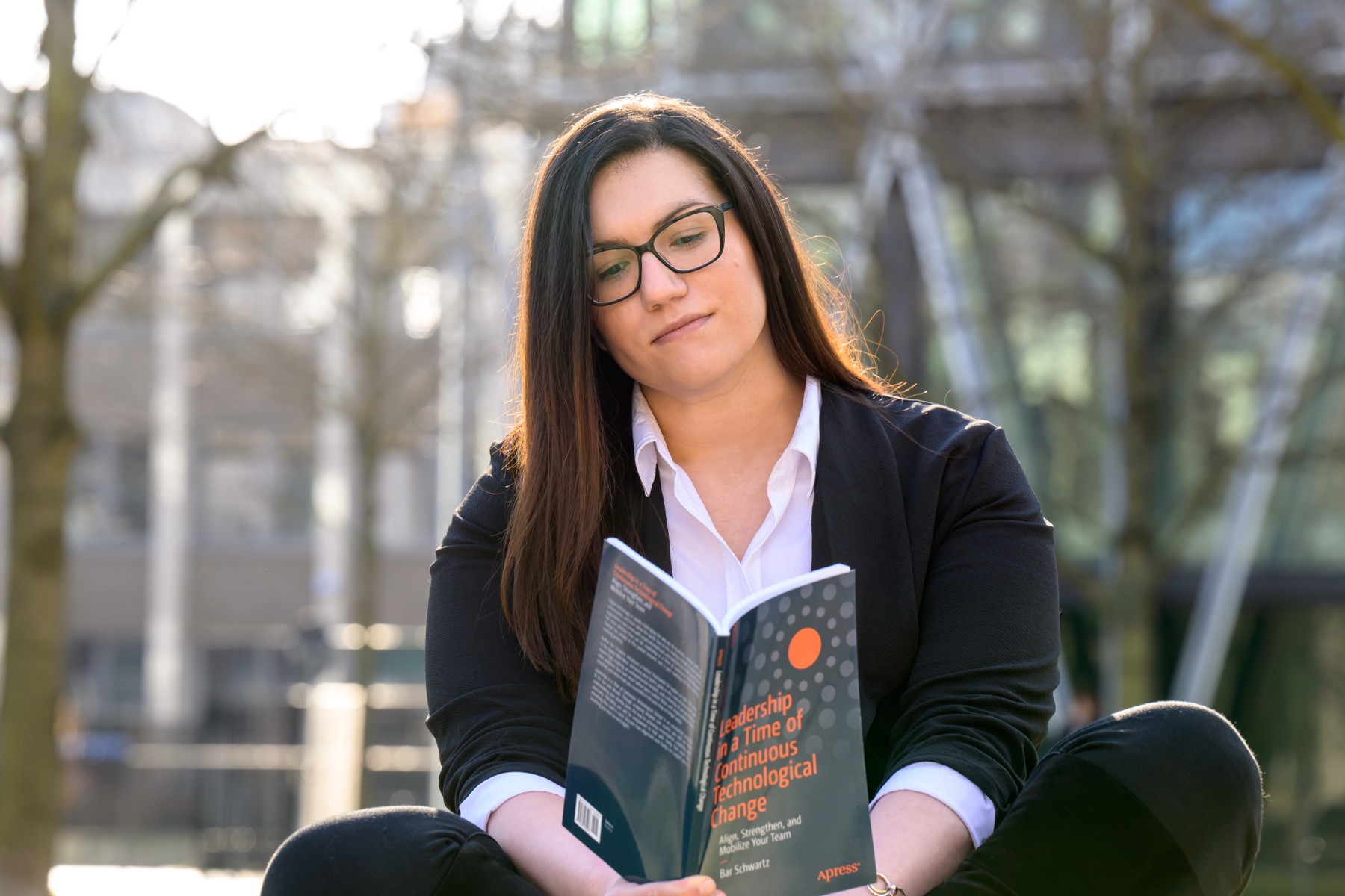 Bar Schwartz, sitting outside an office building, reading Leadership in a Time of Continuous Technological Change
